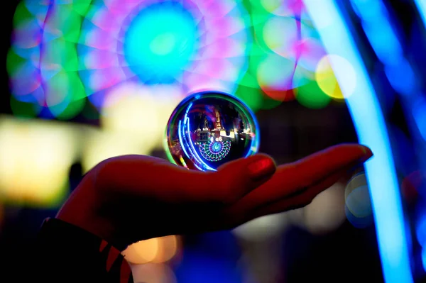 Roda gigante através de uma bola de vidro na palma da sua mão. A atmosfera de celebração e descanso. Aventura nocturna. Cor brilhante.Sílhueta da mão — Fotografia de Stock