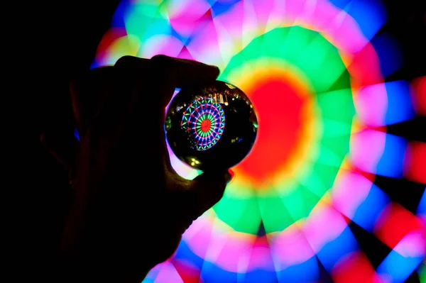 Pariserhjul genom en glaskula på din handflata. Stämningen av fest och resten. Kvällen äventyr. Ljusa färg. Hand siluett — Stockfoto
