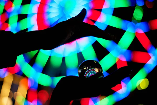 Roda gigante através de uma bola de vidro na palma da sua mão. A atmosfera de celebração e descanso. Aventura nocturna. Cor brilhante.Sílhueta da mão — Fotografia de Stock