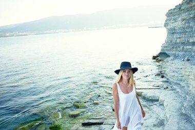 Bir beyaz tunik güzel bir kızı deniz, kayalık sahil Körfezi yürür. Kafasında bir siyah şapka çapında ekledi. Özgürlük ve huzur