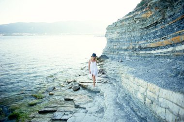 Bir beyaz tunik güzel bir kızı deniz, kayalık sahil Körfezi yürür. Kafasında bir siyah şapka çapında ekledi. Özgürlük ve huzur