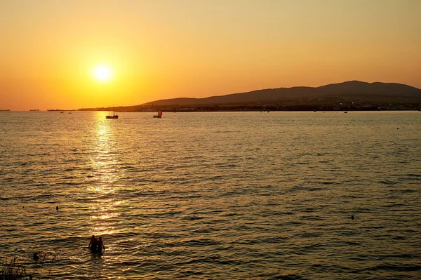 Golden sunset denizde su üzerinde yol. İnsanların yüzme, gemi siluetleri