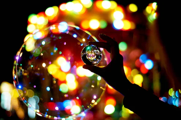 Glass ball in hand, reflection of lights and bokeh.Amusement park