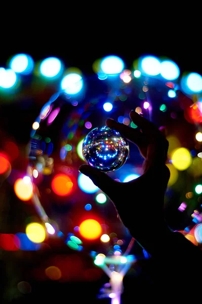 Glass ball in hand, reflection of lights and bokeh.Amusement park