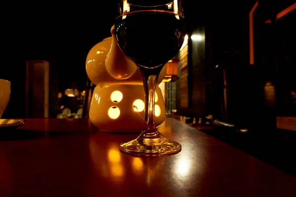 Un bicchiere di vino in un ristorante notturno, una teiera con una candela riscaldante.Una serata accogliente in un'atmosfera romantica — Foto Stock