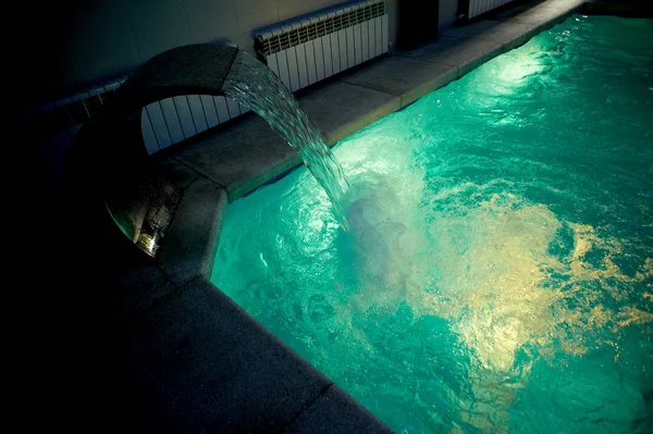 A água na piscina dentro da sala.Parte visível da borda de pedra. Desporto, Spa. Jato de massagem de uma torneira grande — Fotografia de Stock
