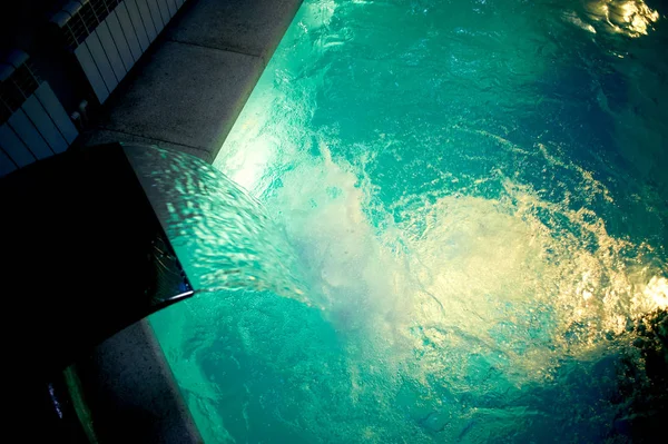 El agua en la piscina dentro de la habitación.Parte visible del borde de piedra. Deportes, Spa. chorro de masaje de un grifo grande —  Fotos de Stock