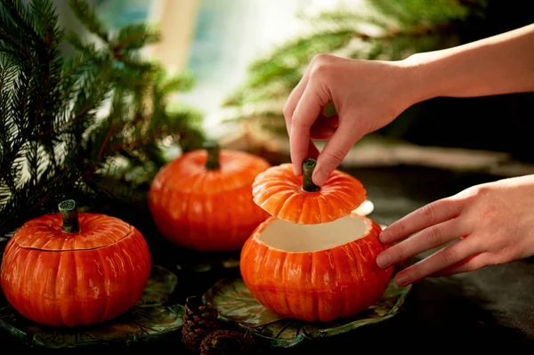 Handgjord keramik i form av pumpor. Christmas tassar. Stämningen av fest och hem komfort. Händer öppna locket på grytan. — Stockfoto