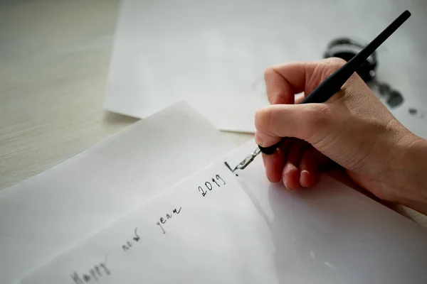 Eine Frauenhand schreibt mit Tinte, einem Füllfederhalter. Schreiben. Der kreative Prozess der Schaffung einer Arbeit.phrase Neujahr 2019. Wunschliste und Pläne — Stockfoto