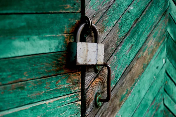 Oude groene deur of muur van een houten huis in rustieke stijl, met de schillen verf. Op de deur hangt een oude metalen sluis — Stockfoto