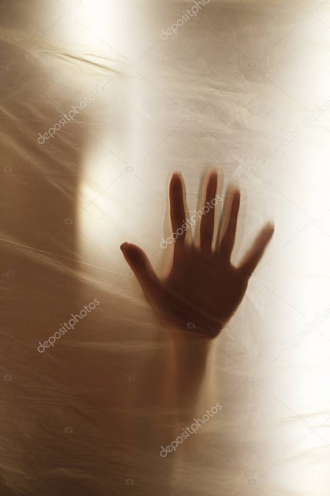 Hands through the clear film.Beautiful delicate feminine hands. A symbol of illusiveness and unreality. Warm gamma, warmth, sun