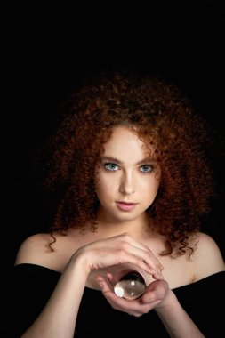 Yemyeşil kıvırcık kırmızı saçlı bir kız. Elinde bir cam küre tutar. Gizem, bir önsezi geleceğin.