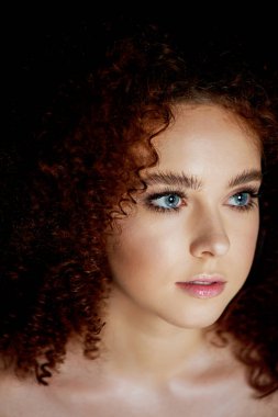 Yemyeşil kıvırcık kırmızı saçlı bir kız. Hassas makyaj ile doll tarzı yanlış eyelashes.