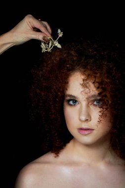 Yemyeşil kıvırcık kırmızı saçlı bir kız. Hassas makyaj sahte kirpik doll tarzı ile. Onun saç makyaj sanatçısı ayarlar