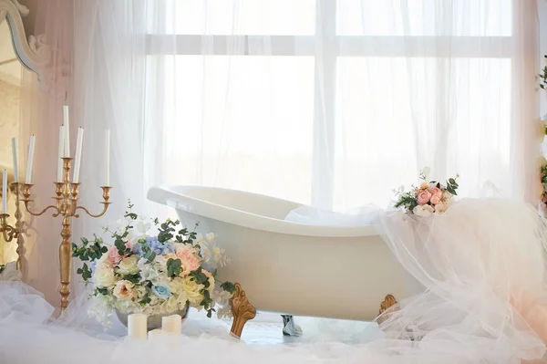 Banyo aslan altın pençeleri üzerinde. Romantizm ve sevgi atmosferi. Hafif iç, şifon, çiçekler.