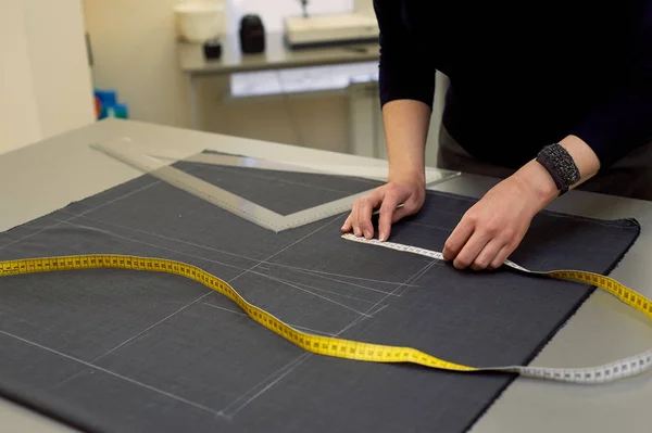 La costurera presenta la tela para cortar usando pulgadas.Manos en la toma . — Foto de Stock