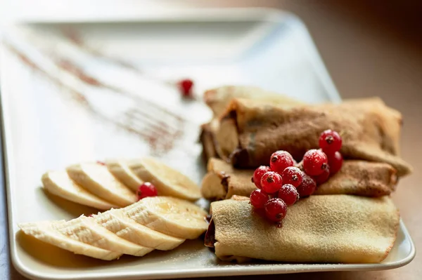 Dessert-hot pancakes with chocolate spread and banana. Decorated with currants.Sweet dessert. — Stock Photo, Image
