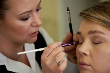 Makyaj sanatçısı gölge fırçası uygular. Profesyonel makyaj. Güzellik endüstrisinde çalışmak. Stil seçimi.