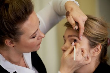 Makyaj sanatçısı gölge fırçası uygular. Profesyonel makyaj. Güzellik endüstrisinde çalışmak. Stil seçimi.