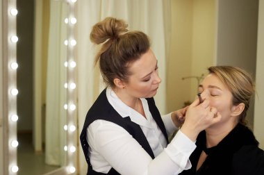 Usta makyaj sanatçısı modelleri yüzüne toz uygulayarak. Makyaj sanatçısı fırça müşterilerine yüz toz uygulamak için. Stil seçimi. Güzellik sektöründe çalışmak.