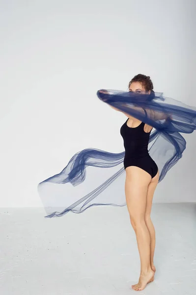 Una gimnasta delgada en medias negras baila con una gasa azul que se desarrolla. Estética de la danza —  Fotos de Stock