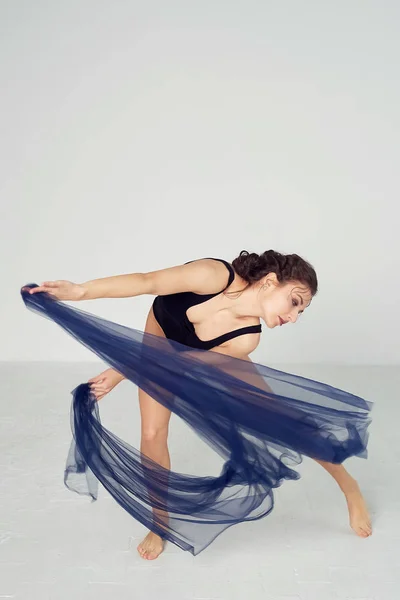 Una gimnasta delgada en medias negras baila con una gasa azul que se desarrolla. Estética de la danza —  Fotos de Stock