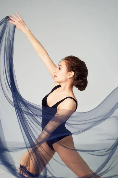 Una gimnasta delgada en medias negras baila con una gasa azul que se desarrolla. Estética de la danza —  Fotos de Stock