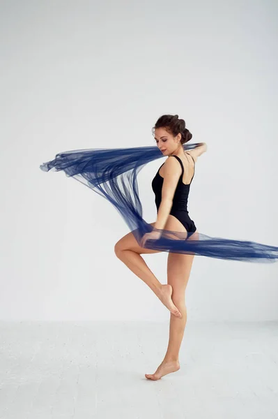 Una gimnasta delgada en medias negras baila con una gasa azul que se desarrolla. Estética de la danza —  Fotos de Stock