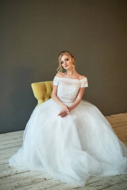 Minyon bir gelin, dantel elbiseli sarışın. Bukleli saçlar. Sandalyede oturuyorum. Gelinler sabah.