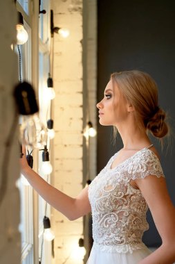 Dantel elbiseli gelin, bir demetle. Ölçülü zarafet. Blonde.Pencereden dışarı bakmak
