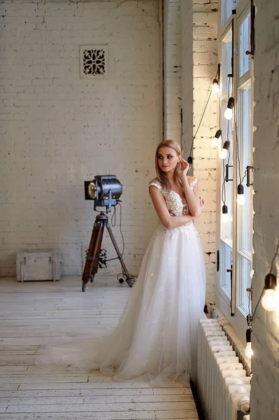 La novia en un vestido de encaje blanco con corpiño bordado, en el interior en estilo loft. Cabello largo, fluido, de color ceniza . — Foto de Stock