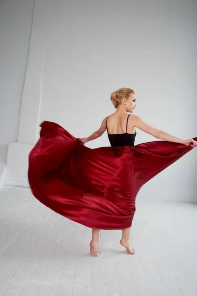 Una gimnasta con un top oscuro y una falda de seda roja. El color de la pasión, de la agresión.Tango. Cuerpo de plástico, aireación, ingravidez y ligereza . —  Fotos de Stock