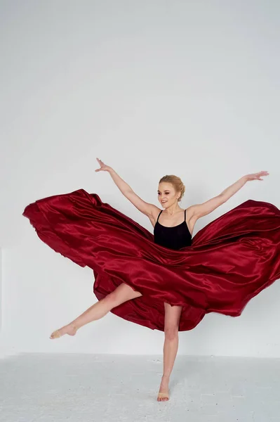 Una gimnasta con un top oscuro y una falda de seda roja. El color de la pasión, de la agresión.Tango. Cuerpo de plástico, aireación, ingravidez y ligereza . —  Fotos de Stock