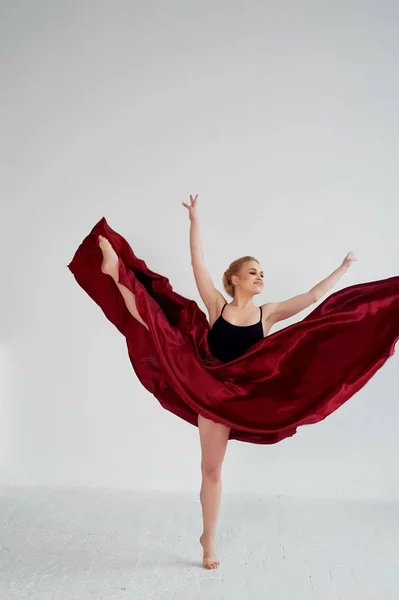 Una gimnasta con un top oscuro y una falda de seda roja. El color de la pasión, de la agresión.Tango. Cuerpo de plástico, aireación, ingravidez y ligereza . —  Fotos de Stock