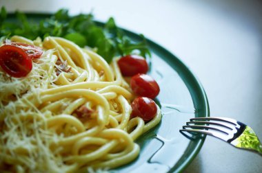 Rendelenmiş Parmesan peyniri ve kiraz domates, arugula ile dekore makarna Carbonara. İtalyan öğle yemeği.