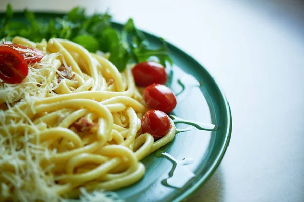 Pasta Carbonara z tartą parmezanem i pomidorami wiśniowym, ozdobiona arugula. Włoski obiad. — Zdjęcie stockowe