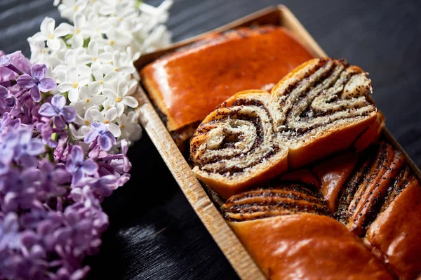 Poppy seed roll , juicy and appetizing.Sprig of lilac. Tea party — Stock Photo, Image