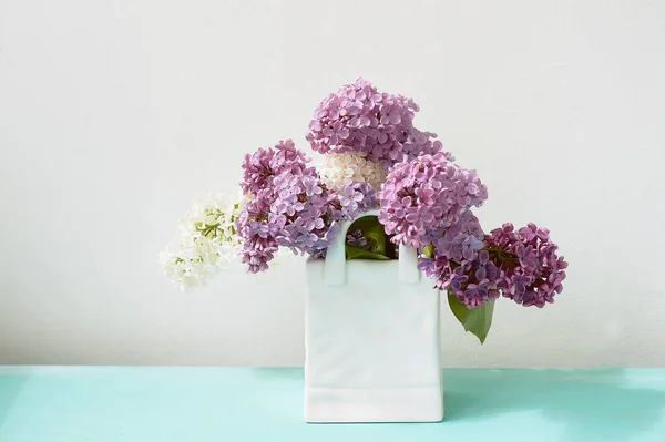 Ramos de lilás branco e roxo. Em um pacote de vaso branco . — Fotografia de Stock