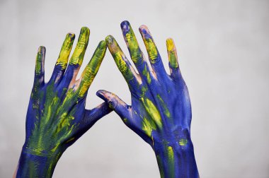 Sarı aksanlı mavi boyalı eller, sanatçının elleri ve yaratıcı kişi. Eller için Yoga
