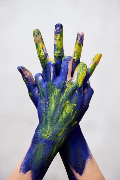 Graceful hands of the artist .Hands in blue and yellow paint. Creator, creativity.Yoga for hands. Fingers locked. Sign of protection and closure.