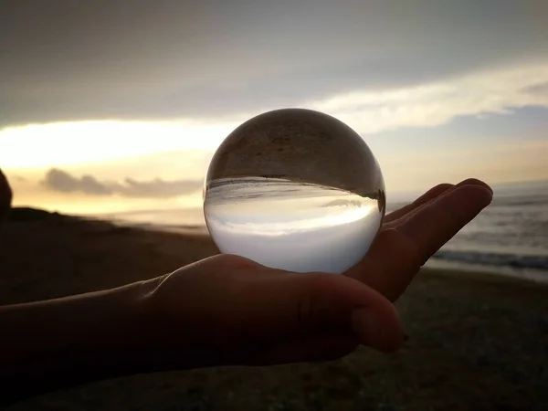 Globe de verre dans la paume de votre main.Reflet de la mer et le coucher du soleil . — Photo