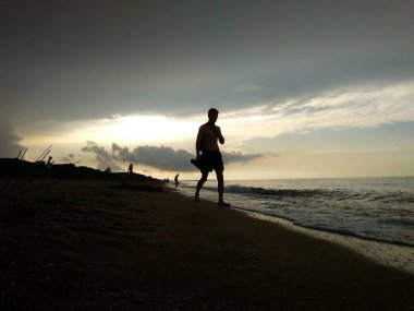 Akşamları deniz arka planda insanların siluetleri. Sunset. A adam kıyı boyunca yürür