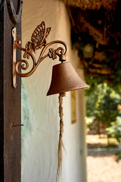 Vecchia campana di metallo vicino alla porta. Retro — Foto Stock