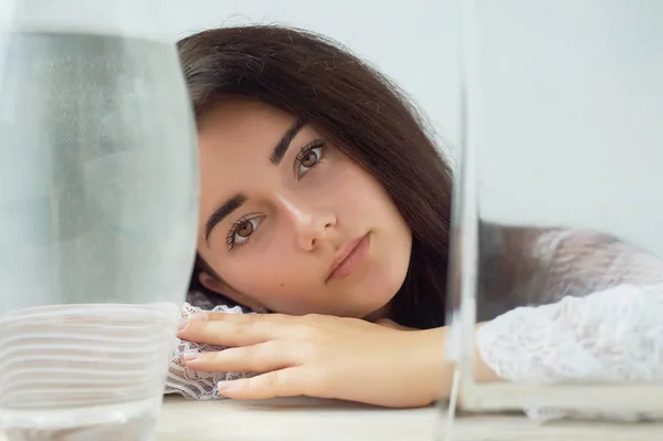 Uma menina com sobrancelhas escuras, olhos castanhos e cabelos escuros. Beleza natural. Sobrancelhas grossas e largas. Vasos com água. Beleza natural — Fotografia de Stock