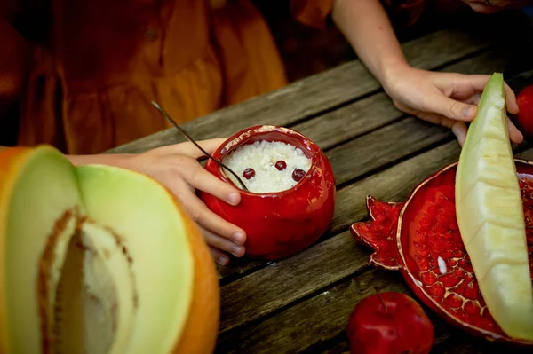 Céramique rouge, fabriquée à la main. Formée comme une grenade. Mains d'enfants autour du pot de bouillie. Petit déjeuner sain — Photo