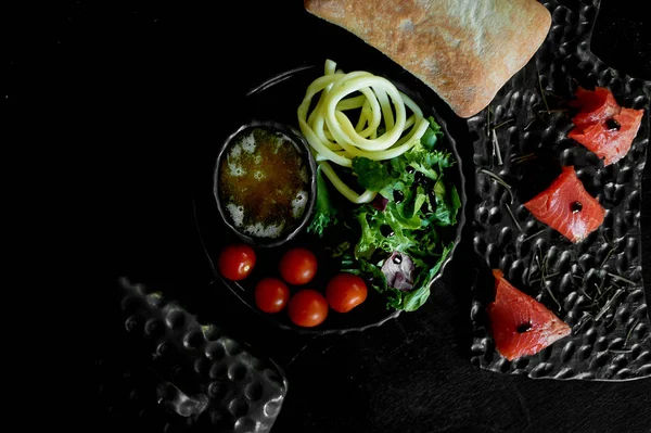 Comida saborosa e saudável. Fundo preto, cerâmica artesanal. Mesa com comida deliciosa e nutritiva. Queijo Cecil, rúcula, mel, peixe vermelho e tomate cereja. Alimentos saudáveis . — Fotografia de Stock