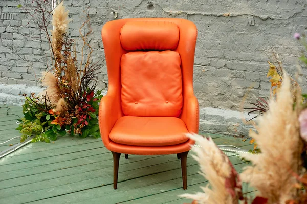 Cadeira de couro falso laranja no terraço de estilo loft ao ar livre.A composição do arranjo casual da grama pampas japonesa — Fotografia de Stock