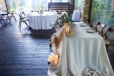 Ziyafet salonu, düğün süsü. Klasik servis, pampalar, mumlar. Koyu bir ağaç..