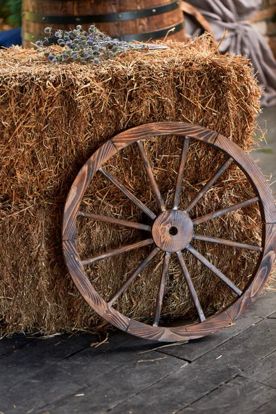 Staré dřevěné kolo z vozíku u kupky sena. Vesnice, vesnická výzdoba. — Stock fotografie