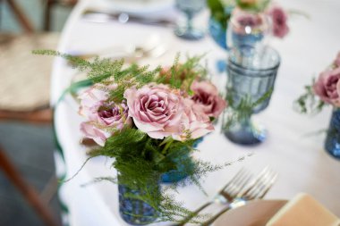 Küçük mavi vazolarda toz güller. Düğün dekoru ya da romantik randevu tasarımı. Çiçek..